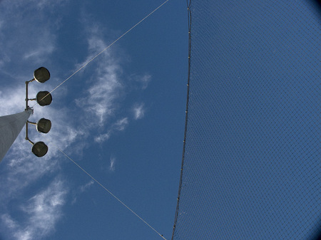 Baseball field light pole with clouds.