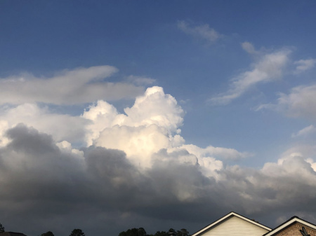 May 23    Clouds tower over rooftops, their power forgotten because of their beauty.